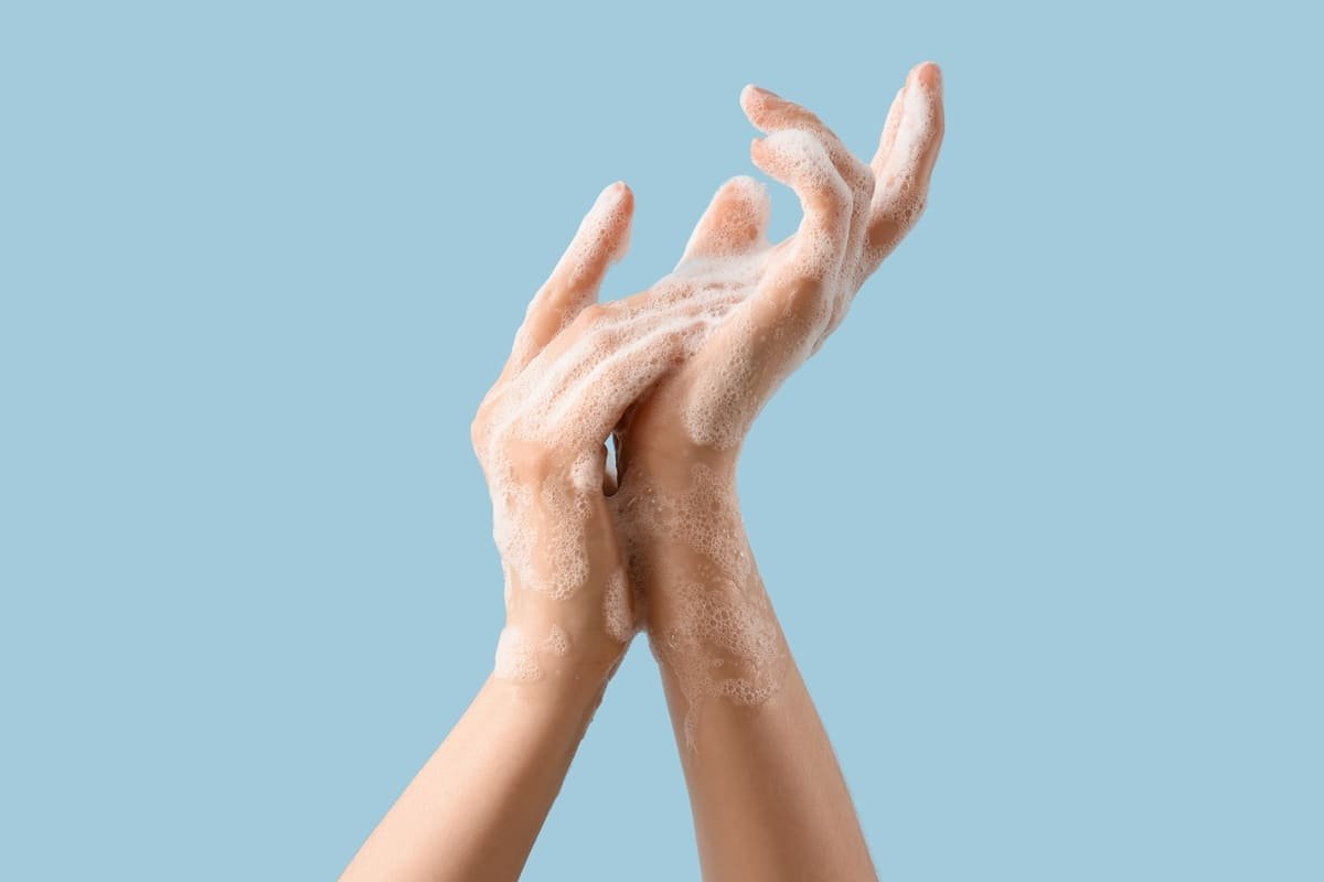 hands washed with soap foam on blue background
