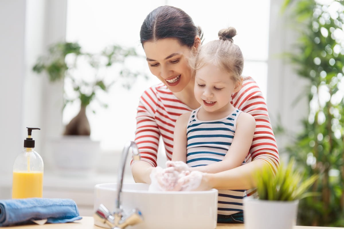 mother and son wash their hands with soap in the sink